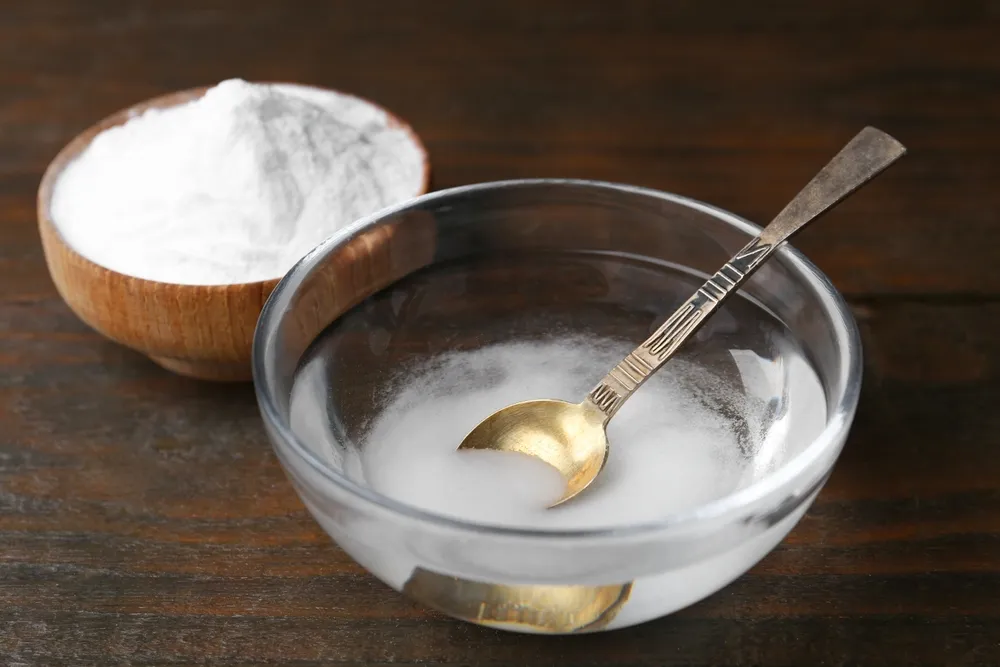 Pote de bicarbonato de sodio con un pequeño bowl con agua, bicarbonato y una cuchara